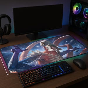 May include: A large, rectangular gaming mousepad featuring a fantasy creature design with a starry background. The mousepad is placed on a wooden desk, with a keyboard, mouse, and computer monitor visible. The mousepad has a colorful LED edge.