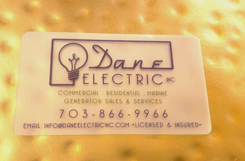 May include: A rectangular, semi-translucent business card featuring the black text Dane Electric Inc, a lightbulb icon, and the services: Commercial, Residential, Marine, Generator Sales & Services, phone number 703-866-9966, email, and Licensed & Insured.