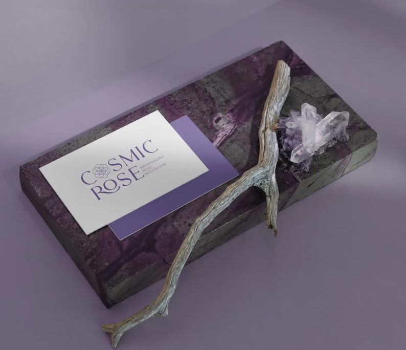 May include: A rectangular purple stone slab featuring a white business card with the text COSMIC ROSE, a weathered grey wooden twig, and a cluster of clear quartz crystals. The card also displays smaller text reading BREATHWORK REIKI MEDITATION.