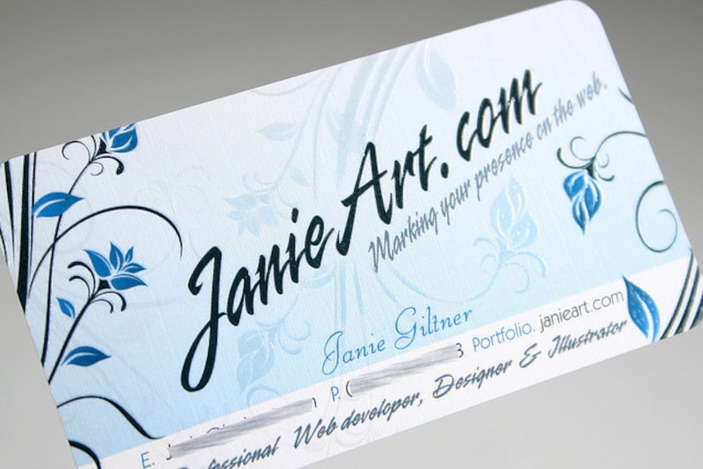 K&ouml;nnte beinhalten: Eine rechteckige Visitenkarte mit abgerundeten Ecken, hellblauem Hintergrund und dunkelblauen Blumenmotiven. Der Text lautet JanieArt.com, Marking your presence on the web, Janie Giltner, Portfolio.janieart.com und Professional Web developer, Designer & Illustrator.