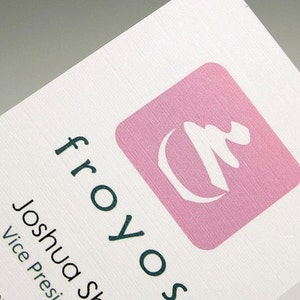 May include: A white business card with the text "froyo.s" in dark green letters. The text "Joshua S" and "Vice President" are also in dark green letters. A pink square with a white stylized tree design is in the upper right corner.