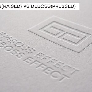 May include: A light gray textured paper surface featuring the text EMBOSS(RAISED) VS DEBOSS(PRESSED) at the top. Below, a rectangular logo outline is embossed, while the words EMBOSS EFFECT and DEBOSS EFFECT are debossed into the paper material.