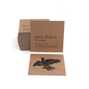 May include: A stack of square brown paper business cards with black text reading Jenny DuPont, graphic designer, call 415.577.0921, write jennylynndupont@gmail.com, and a separate card featuring a black ink illustration of a bird with wings spread.