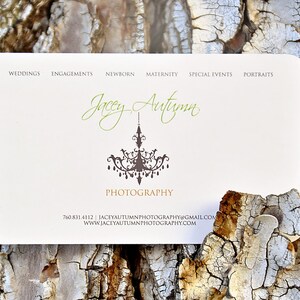 May include: A rectangular white business card with rounded corners featuring the text Jacey Autumn Photography in green and gold script and print. A dark brown chandelier graphic is centered. Text includes services, phone number, email, and website.