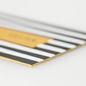 May include: A close-up of a black and white striped card with a gold border. The card has a yellow rectangle in the top left corner.