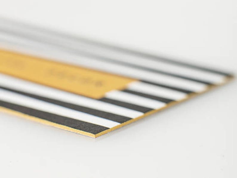 May include: A close-up of a black and white striped card with a gold border. The card has a yellow rectangle in the top left corner.