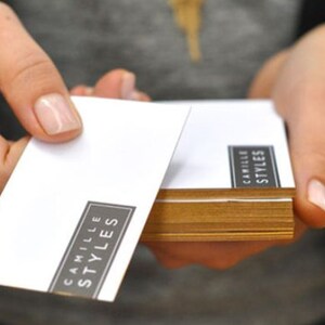 May include: A stack of white business cards with the text "Camille Styles" printed in black.
