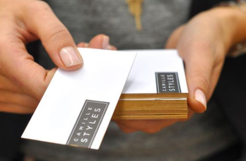 May include: A stack of white business cards with the text "Camille Styles" printed in black.