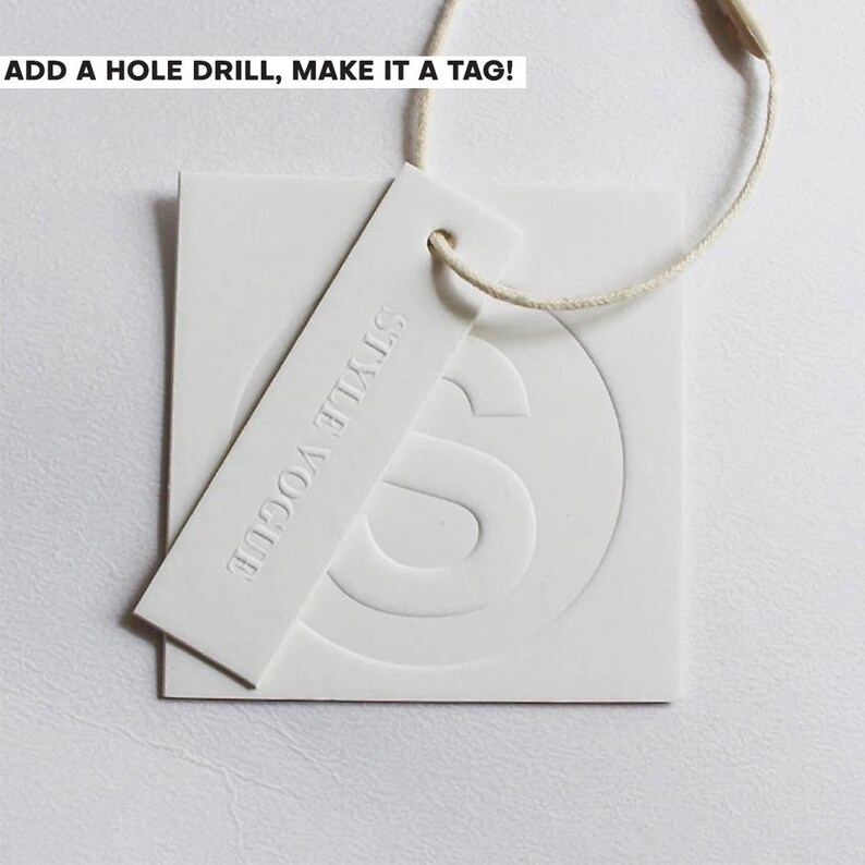 May include: White tag with the text "STYLE VOGUE" embossed on a rectangular tag, with a square tag behind it. The square tag has a large "S" embossed on it. The text "ADD A HOLE DRILL, MAKE IT A TAG!" is at the top.