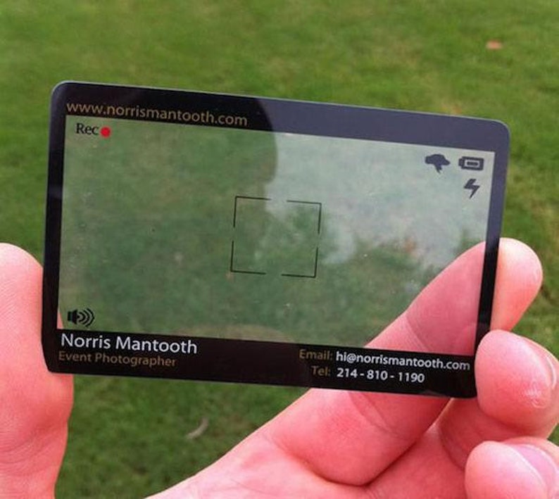 Puede incluir: Una tarjeta de visita rectangular transparente con bordes negros, dise&ntilde;ada para parecer un visor de c&aacute;mara. Muestra el texto Norris Mantooth, Event Photographer, el sitio web www.norrismantooth.com, el correo hi@norrismantooth.com y el tel&eacute;fono 214-810-1190.