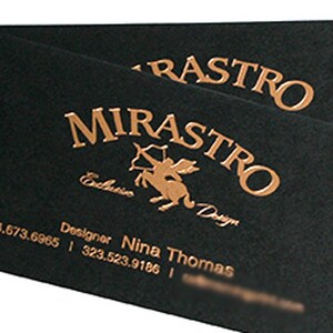 May include: Two rectangular black business cards featuring metallic copper foil stamping. The text reads MIRASTRO, Exclusive Design, and Designer Nina Thomas, along with two phone numbers. A centaur graphic with a bow and arrow is centered.
