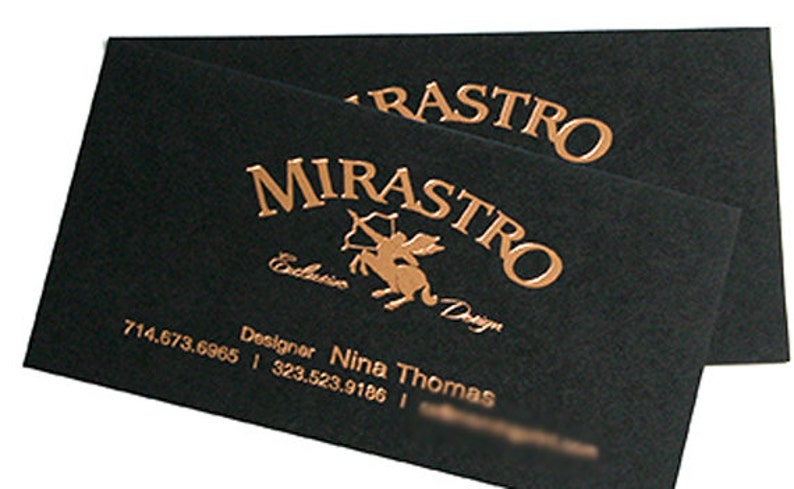 May include: Two rectangular black business cards featuring metallic copper foil stamping. The text reads MIRASTRO, Exclusive Design, and Designer Nina Thomas, along with two phone numbers. A centaur graphic with a bow and arrow is centered.