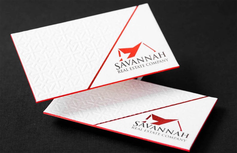 May include: Two white business cards with a red border and a red diagonal line. The cards feature a red house logo with the text "SAVANNAH REAL ESTATE COMPANY" in black.