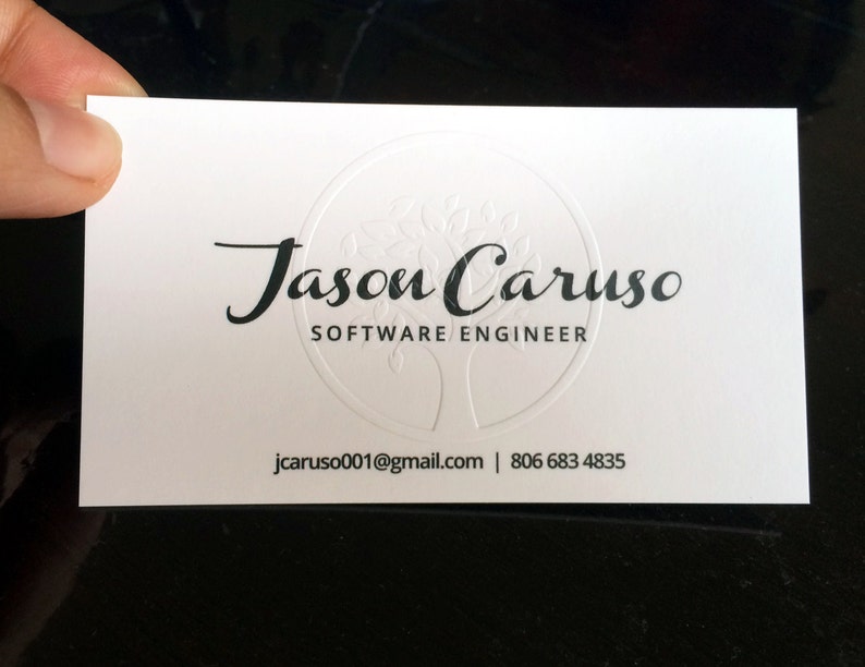 May include: A white business card with the name "Jason Caruso" and the title "Software Engineer" printed in black. The card also includes an email address and phone number. A tree design is embossed in the center.