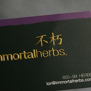 Puede incluir: Una tarjeta de visita rectangular con fondo negro y un borde superior morado. La tarjeta presenta texto dorado en relieve que dice immortalherbs y caracteres chinos, con la informaci&oacute;n de contacto 855-99 HERBS y lori@immortalherbs.com.