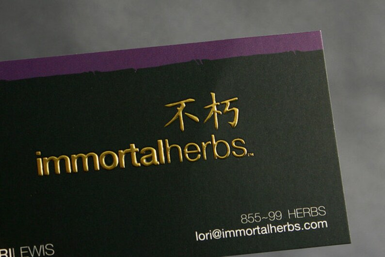 Puede incluir: Una tarjeta de visita rectangular con fondo negro y un borde superior morado. La tarjeta presenta texto dorado en relieve que dice immortalherbs y caracteres chinos, con la informaci&oacute;n de contacto 855-99 HERBS y lori@immortalherbs.com.