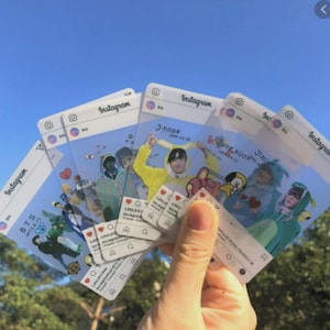 Puede incluir: Un conjunto de tarjetas de pl&aacute;stico transparente dise&ntilde;adas para parecer publicaciones de Instagram, con varios miembros del grupo musical BTS. Cada tarjeta muestra un encabezado de perfil, una imagen central y una interfaz de red social.