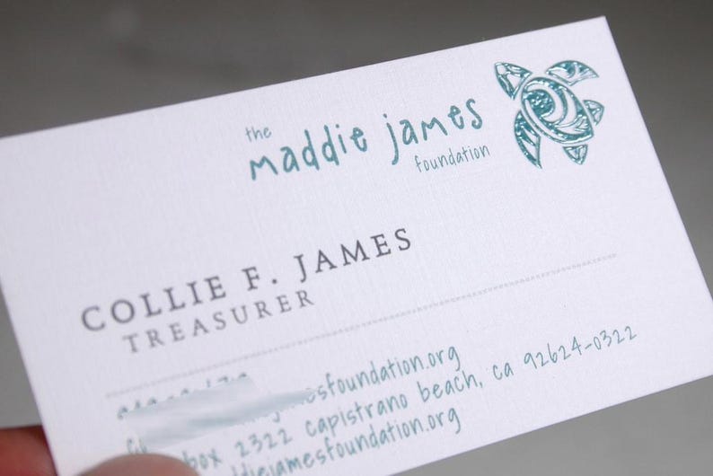 K&ouml;nnte beinhalten: Eine wei&szlig;e Visitenkarte mit dem Text the maddie james foundation in Blaugr&uuml;n, einer blaugr&uuml;nen Meeresschildkr&ouml;ten-Grafik und dem Namen COLLIE F. JAMES, TREASURER in Dunkelgrau. Die Karte enth&auml;lt eine Adresse in Capistrano Beach, CA 92624-0322.