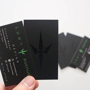 May include: A set of rectangular black business cards featuring the text LOST AVENUE DESIGN in green, a green star-like logo, and contact information including an email address, phone number, and social media handles printed in white and green.