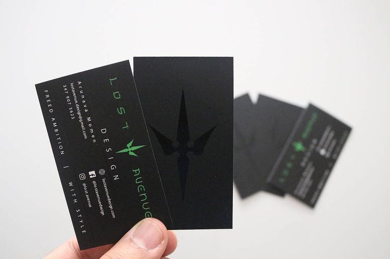 May include: A set of rectangular black business cards featuring the text LOST AVENUE DESIGN in green, a green star-like logo, and contact information including an email address, phone number, and social media handles printed in white and green.