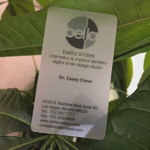 May include: A rectangular, semi-translucent business card for Bella Smiles, featuring a circular logo, the name Dr. Casey Chow, and contact details including the address 6040 S. Rainbow Blvd, Suite B2, Las Vegas, Nevada 89118, phone, fax, and email.