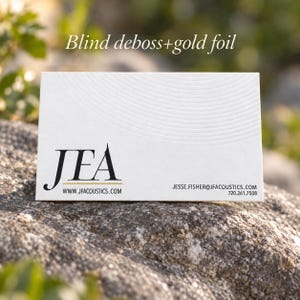 Puede incluir: Una tarjeta de visita rectangular blanca con el texto negro JEA, el sitio web www.jfacoustics.com, el correo jesse.fisher@jfacoustics.com y el n&uacute;mero 720.261.7508. La tarjeta tiene un patr&oacute;n de relieve ciego y detalles en pan de oro.