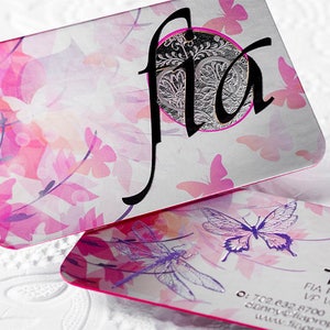 May include: Two business cards with a pink and purple floral design. The top card has the word "fla" in black script with a silver circle behind it. The bottom card has the text "Danny Bense" and "FIA Property Services" in black text.