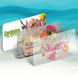 May include: Three rectangular clear acrylic signs with rounded corners. The first sign features green text reading Gardening and 888.555.274 with pink roses. The second shows Floral Arrangement text on a wood background. The third has a hello floral wreath.