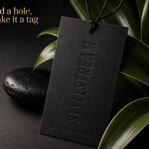 May include: A rectangular black tag with a hole at the top and a black string loop. The tag features the embossed text STYLISTREAM vertically and the website URL WWW.STYLISTREAM.COM at the bottom. The text Add a hole, make it a tag is visible.