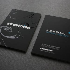 K&ouml;nnte beinhalten: Schwarze und wei&szlig;e Visitenkarte mit dem Text "Studioism" und einem wirbelnden Design. Auf der R&uuml;ckseite der Karte steht der Text "Adam Ismail Graphic Designer" und die Website-Adresse "adam@studioish.com".