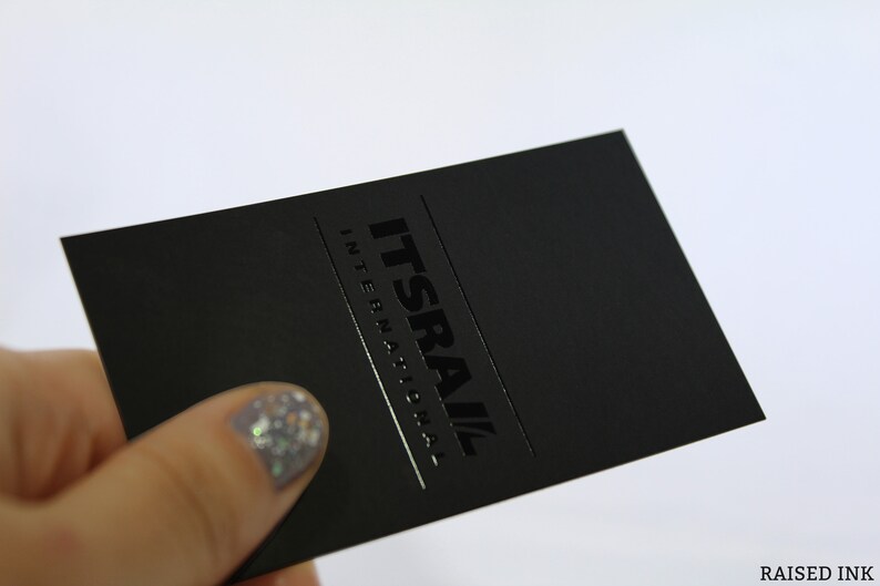 May include: A rectangular black business card featuring the text ITSRAIL INTERNATIONAL in a glossy raised ink finish. The card has a matte black surface with the company name printed in a bold, dark font, creating a subtle contrast between the textures.