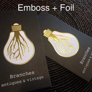 May include: Two black business cards with a gold foil design of a lightbulb with tree-like roots. The cards have the text "Branches antiques & vintage" in white. The words "Emboss + Foil" are at the top.