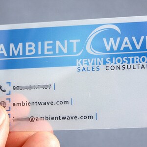 May include: A rectangular, semi-transparent business card featuring a blue gradient header with the white text AMBIENT WAVE. Below, the name KEVIN SJOSTROM and SALES CONSULTANT are printed, followed by contact icons for phone, website, and email.