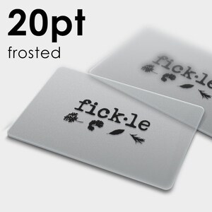 May include: Two rectangular 20pt frosted business cards with rounded corners. Each card features the black text "fick&middot;le" printed in a lowercase serif font, accompanied by a small graphic of four distinct leaves positioned directly below the text.