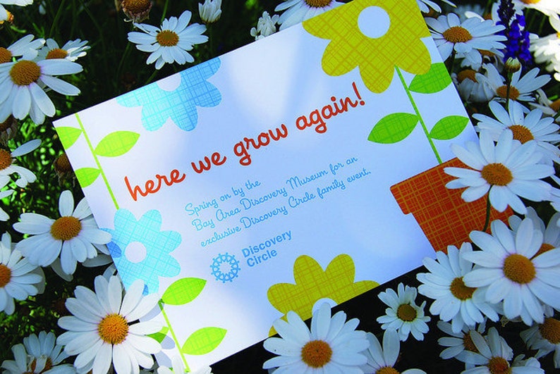 May include: A rectangular white card featuring the orange text here we grow again! and additional event details for the Bay Area Discovery Museum. The card is decorated with blue and yellow flower illustrations and an orange patterned flower pot.
