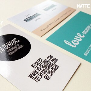 May include: Three rectangular business cards displayed on a surface. One card is white with a black circle and text reading VII DESIGNS, RYAN FOY, and contact details. Another is white with tan accents. The third is teal with white text reading love creative blog.