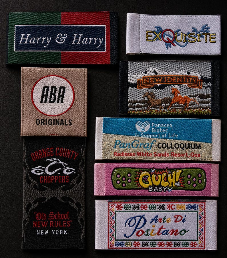 May include: A collection of eight rectangular woven fabric labels featuring various embroidered designs and text including Harry & Harry, Exquisite, ABA Originals, New Identity with horses, Panacea Biotec, Orange County Choppers, Ouch Baby, and Arte Di Positano.