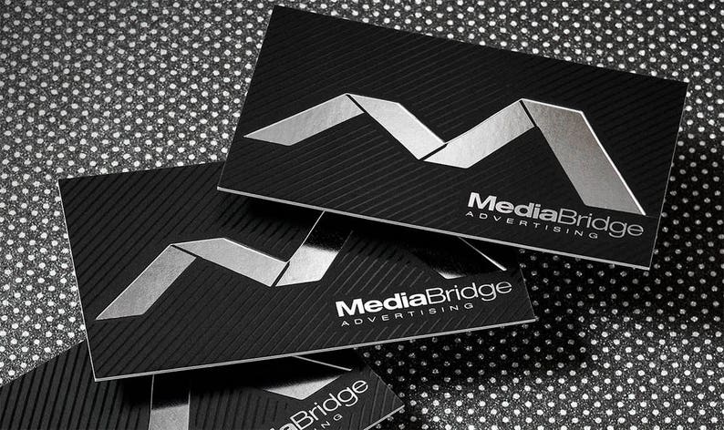 May include: Close-up of black business cards with a silver embossed logo and the text "MediaBridge Advertising".
