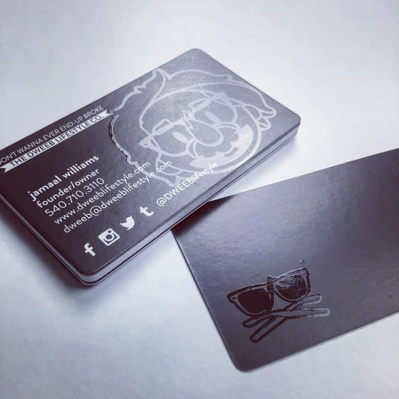 May include: Two rectangular black business cards with a glossy finish. One card displays the text "DON'T WANNA EVER END-UP BROKE THE DWEEB LIFESTYLE CO.", contact details for Jamaal Williams, social media icons, and a line-art character illustration.