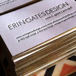 May include: A stack of white business cards with gold-gilded edges. The text ERIN GATES DESIGN is embossed in large capital letters, followed by erin t. gates | principal, the website www.eringatesdesign.com | www.elementsofstyleblog.com, and phone numbers.