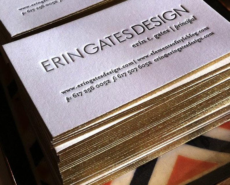 May include: A stack of white business cards with gold-gilded edges. The text ERIN GATES DESIGN is embossed in large capital letters, followed by erin t. gates | principal, the website www.eringatesdesign.com | www.elementsofstyleblog.com, and phone numbers.