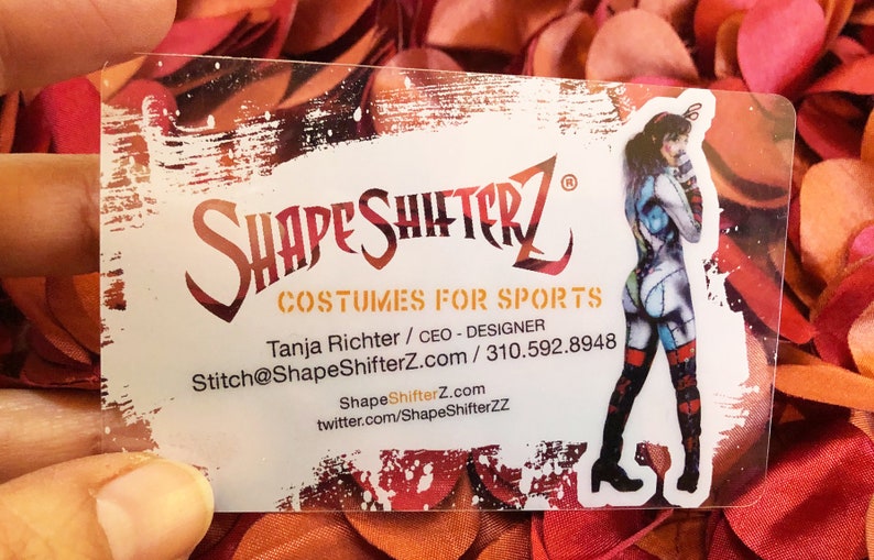Puede incluir: Una tarjeta de visita rectangular y transparente con el texto SHAPESHIFTERZ COSTUMES FOR SPORTS, Tanja Richter / CEO - DESIGNER, Stitch@ShapeShifterZ.com / 310.592.8948, ShapeShifterZ.com y twitter.com/ShapeShifterZZ junto a un gr&aacute;fico de una persona disfrazada.