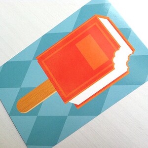 May include: A rectangular sticker featuring a graphic illustration of an orange popsicle with a white cream center and a wooden stick. The popsicle has a bite mark on the right side. The background consists of a light blue geometric diamond pattern.