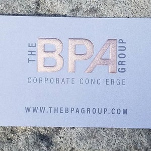May include: A light blue business card with the text "THE BPA GROUP CORPORATE CONCIERGE" in a rose gold color. The website address www.thebpagroup.com is printed at the bottom in gray.