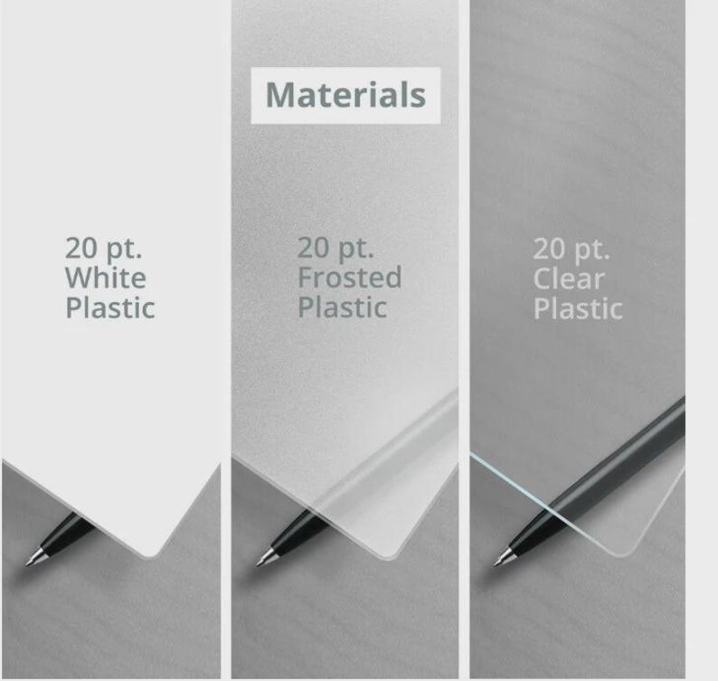 May include: Three rectangular plastic sheets labeled Materials. The first is 20 pt. White Plastic, the second is 20 pt. Frosted Plastic, and the third is 20 pt. Clear Plastic. Each sheet is partially overlapping a black pen tip at the bottom corner.