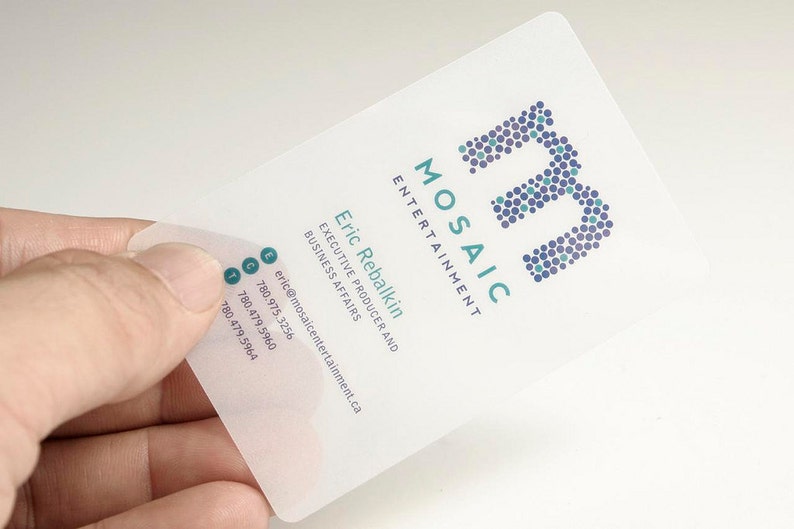 May include: A translucent, rectangular business card featuring the Mosaic Entertainment logo in purple and teal dots. The text includes the name Eric Rebalkin, the title Executive Producer and Business Affairs, an email address, and three phone numbers.