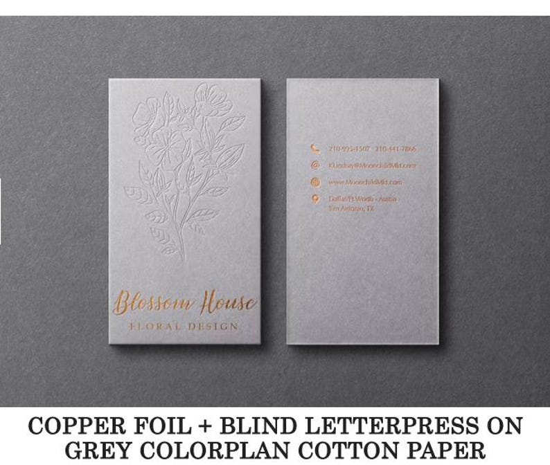 May include: Two rectangular grey business cards featuring copper foil text and blind letterpress floral designs. The front displays the text Blossom House Floral Design, while the back lists contact details including phone, email, and website.