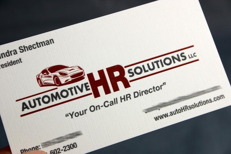 K&ouml;nnte beinhalten: Eine wei&szlig;e Visitenkarte mit einer roten Grafik eines Sportwagens und dem Text Automotive HR SOLUTIONS LLC. Die Karte enth&auml;lt den Schriftzug Your On-Call HR Director, eine Website-Adresse sowie teilweise Kontaktinformationen in roter und schwarzer Tinte.