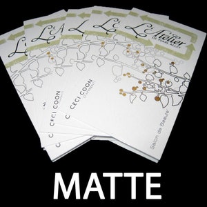 May include: A stack of white rectangular business cards featuring a black line drawing of a leafy branch with gold-colored berries. The text reads L'Atelier de Pearl Alley, Ceci Coon D'Apprenti, and Salon de Beaute, with the word MATTE below.