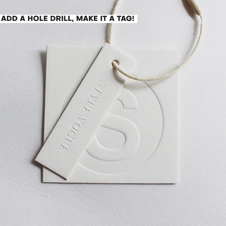May include: A white square tag and a rectangular white tag with the text STYLE VOGUE embossed on it. Both tags are made of thick paper and are connected by a thin beige string. The text ADD A HOLE DRILL, MAKE IT A TAG! is visible at the top.